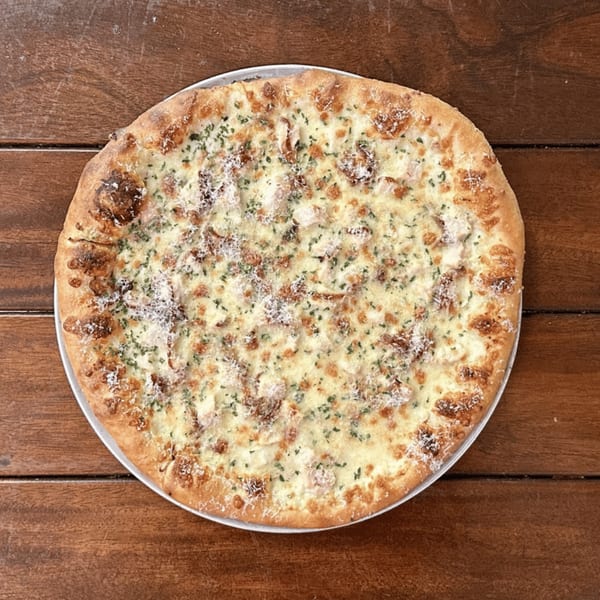 Miko's Calitalia white pizza with chicken, cheese, and herbs on a wooden table.